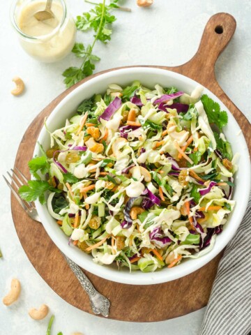 Bowl of curry coleslaw on a wooden cutting board