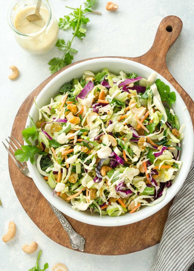 Bowl of vegan coleslaw on a wooden cutting board