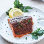 Air fryer salmon on a plate with lemon and parsley