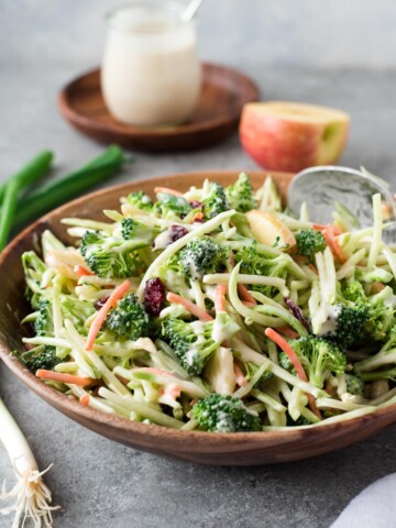 Broccoli slaw in a bowl with jar of dressing behind