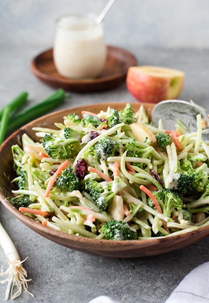 Broccoli slaw in a bowl with jar of dressing behind