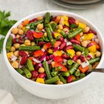 Three bean salad in white bowl with spoon inside