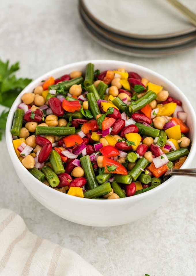 Three bean salad in white bowl with spoon inside