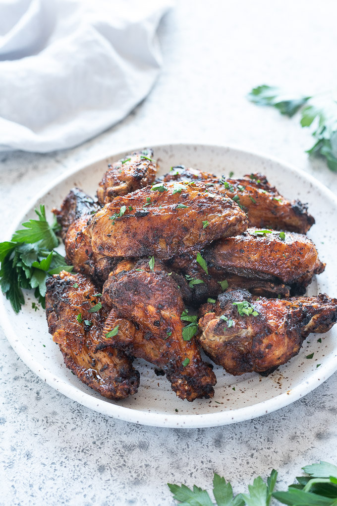 Air fryer chicken wings on a white plate with parsley