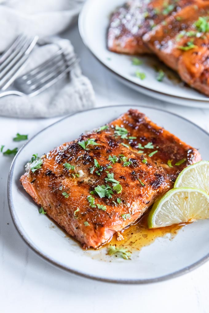 Blackened salmon filet on a white plate with parsley and lime