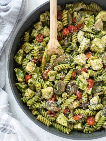Chicken pesto pasta in a skillet with wooden spoon