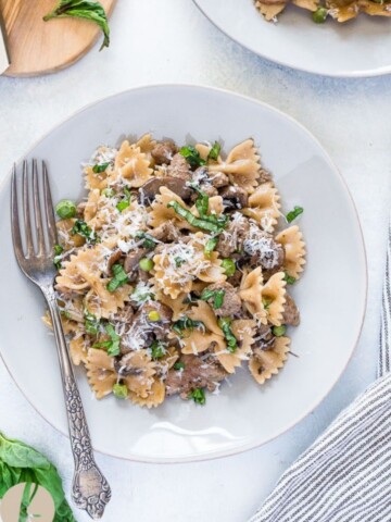 Sausage and bow tie pasta on a plate with a fork.