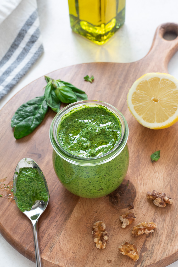 Spinach pesto in a jar with lemon, walnuts and basil alongside
