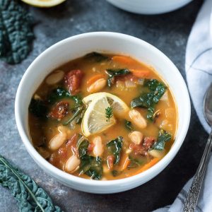 White bean and kale soup in a bowl with lemon and thyme
