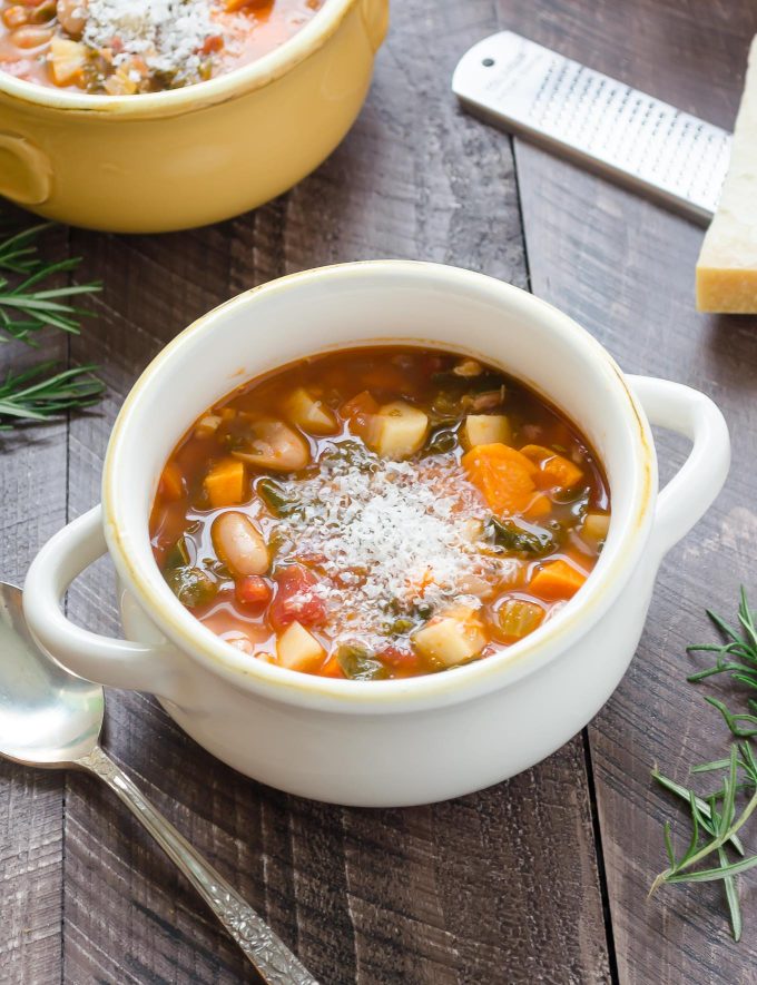 Winter minestrone soup in a white bowl with parmesan on top