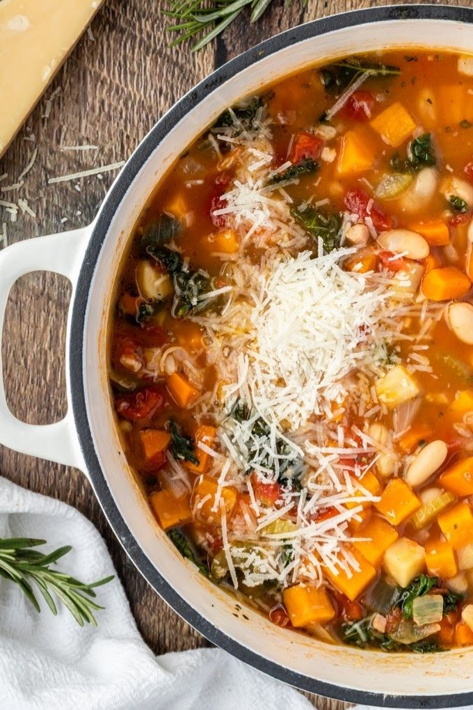 Winter minestrone soup in a white Dutch oven with parmesan on top