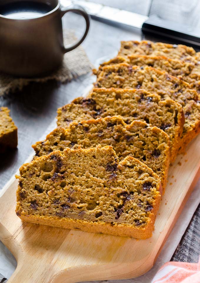 Healthy pumpkin bread sliced with a cup of coffee in the background