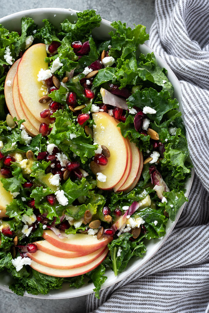 Kale and apple salad with pomegranate in a serving bowl