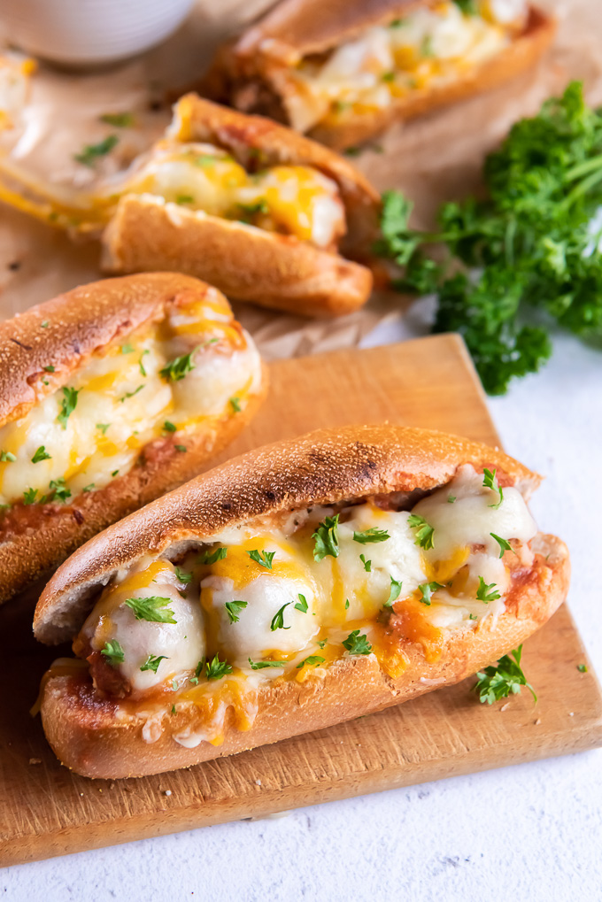 Meatball subs on cutting board with fresh parsley