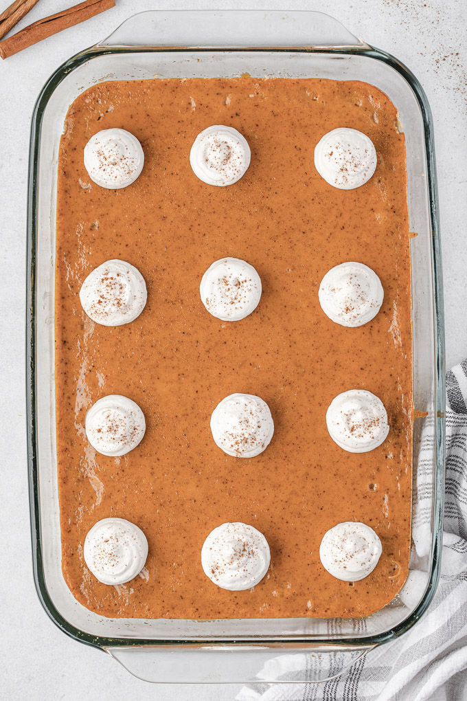 Pumpkin pie bars in baking dish with whipped cream dollops
