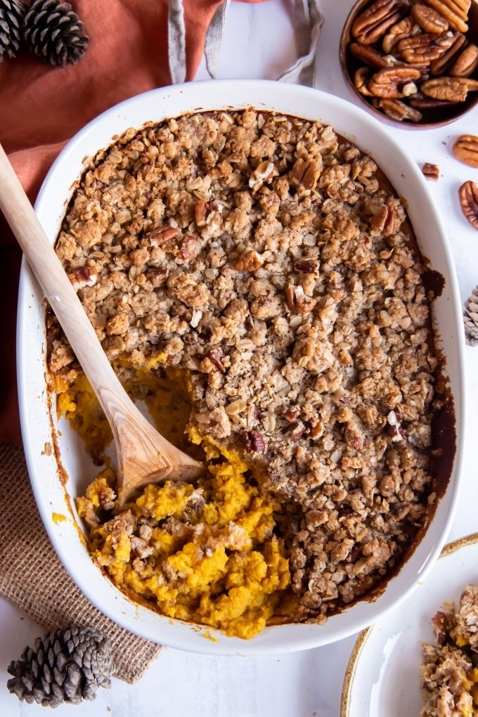 Spoon digging into butternut squash casserole with streusel topping
