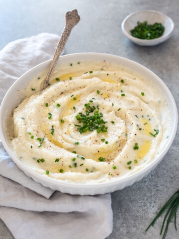 Bowl of garlic mashed cauliflower with spoon digging in