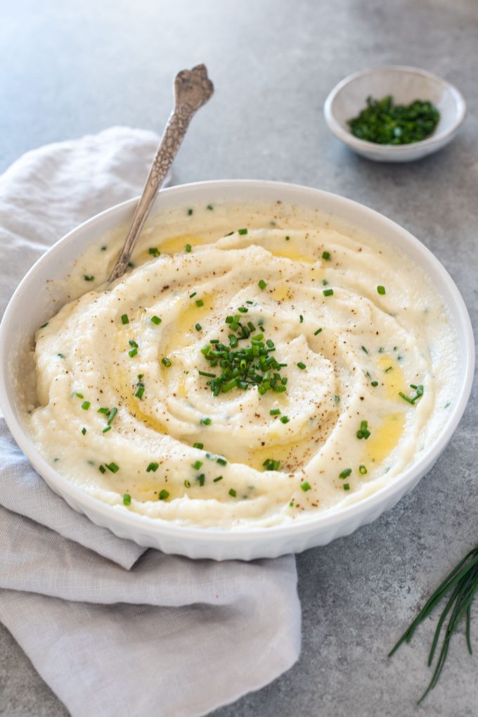 Bowl of garlic mashed cauliflower with spoon digging in