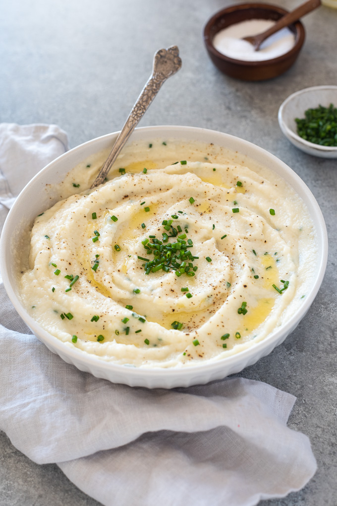 Garlic mashed cauliflower in a white bowl with a spoon