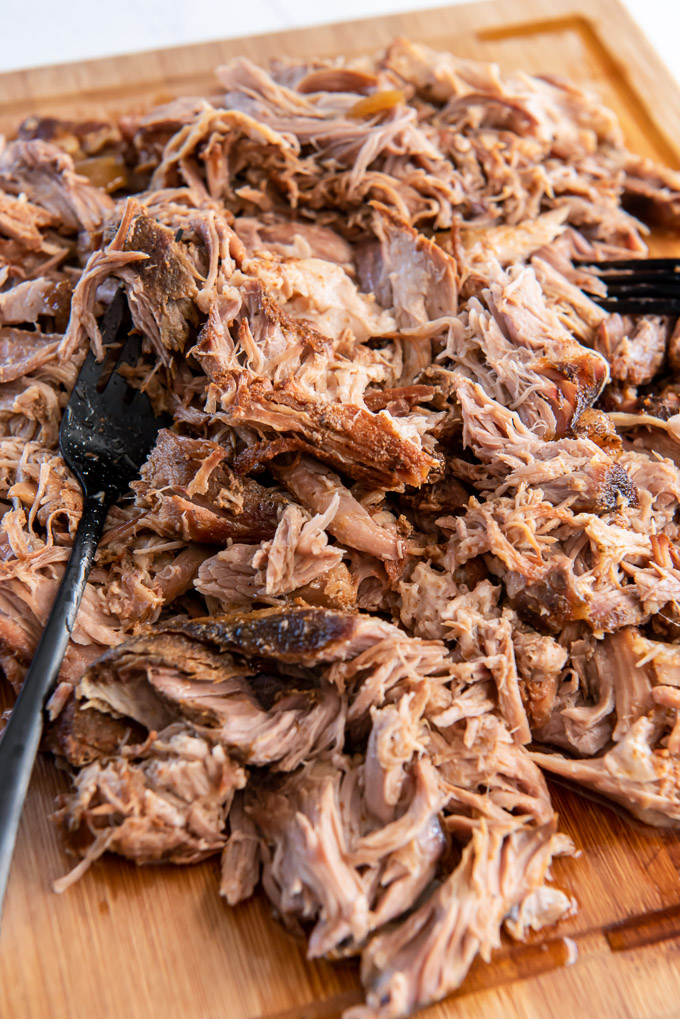 Slow cooker pulled pork shredded with forks on a cutting board