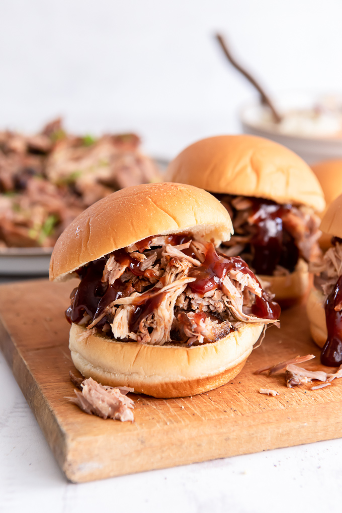 Pulled pork sandwich on a cutting board with bbq sauce