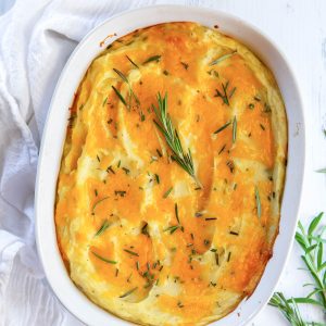 Twice baked mashed potatoes in a baking dish with rosemary on top