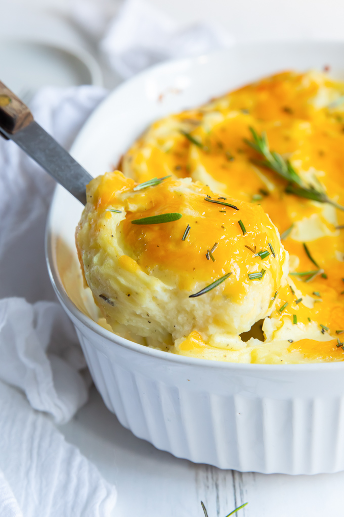 Spoonful of twice baked mashed potatoes lifting out of baking dish