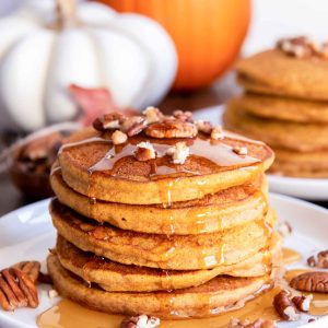 Stack of healthy pumpkin pancakes with pecans and syrup