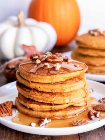 Stack of healthy pumpkin pancakes with pecans and syrup