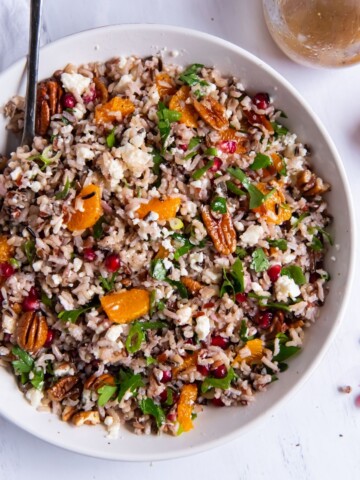 Wild rice salad in a white bowl with a serving spoon