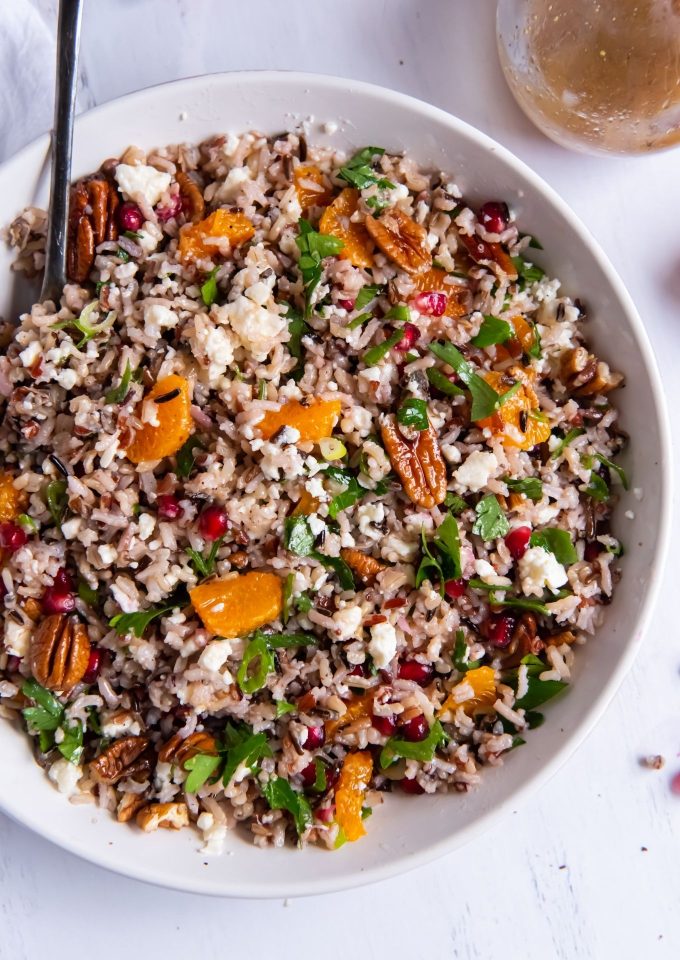 Wild rice salad in a white bowl with a serving spoon