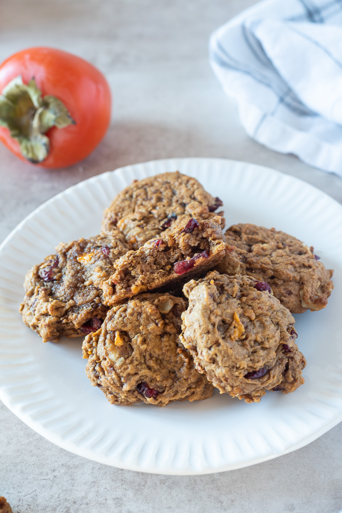 Pile of persimmon cookies on a plate with bite out of top cookie