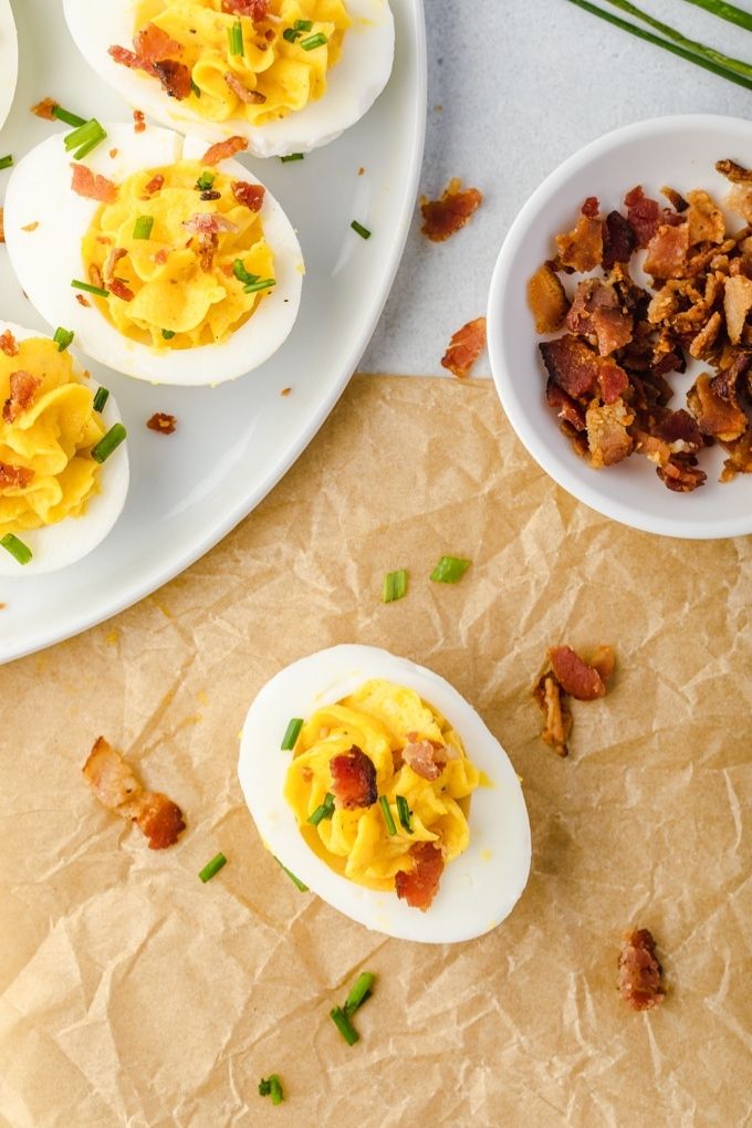 Bacon deviled eggs on a plate with bowl of bacon