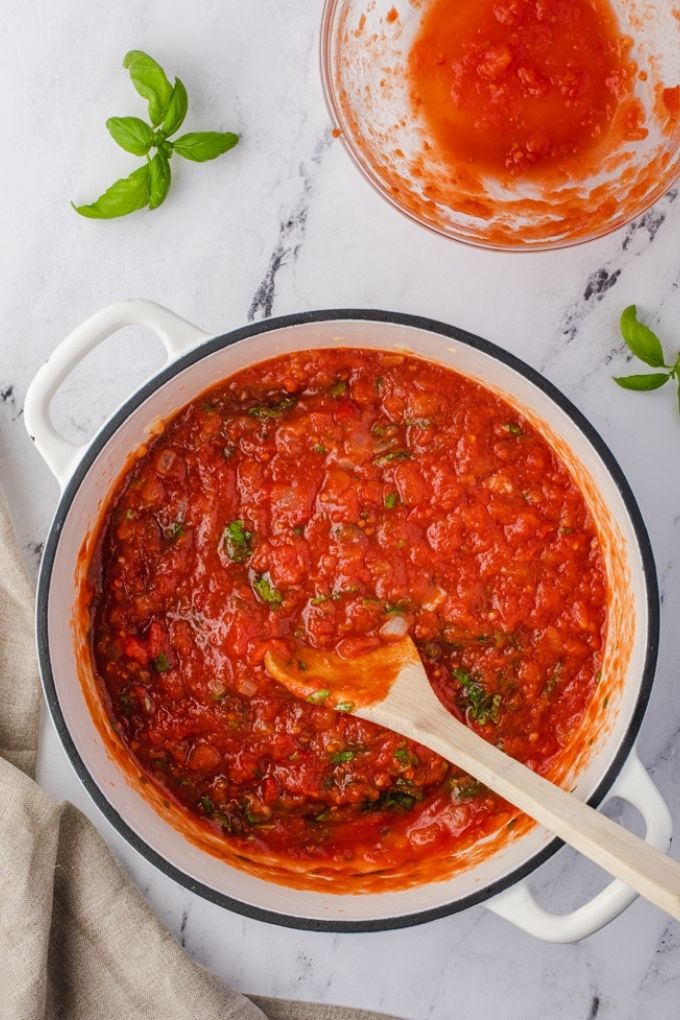 Easy marinara sauce in a white Dutch oven with wooden spoon