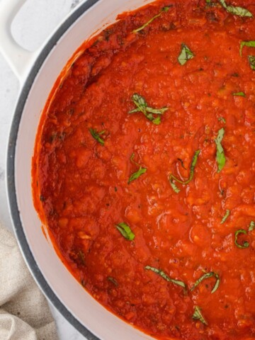 Homemade marinara sauce in a dutch oven with basil on top