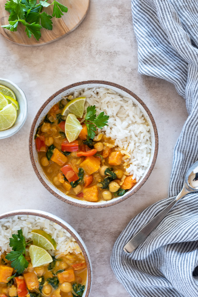 Bowl of chickpea curry with rice, limes and cilantro
