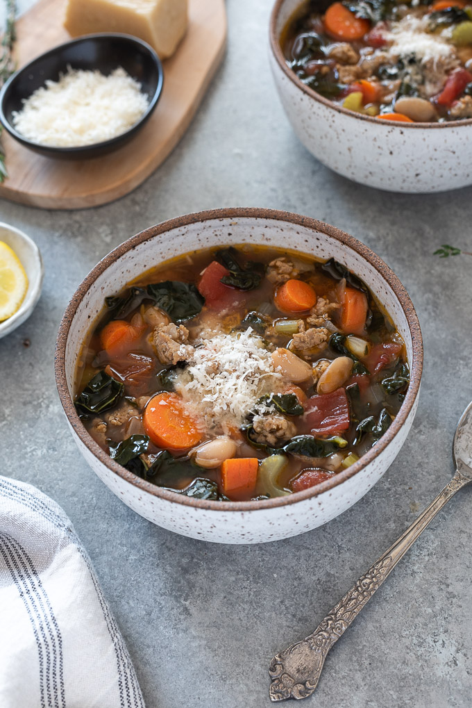Bowl of sausage kale soup with parmesan cheese on top