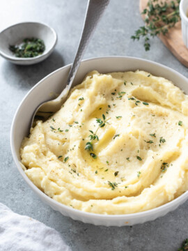 Parsnip puree in a white bowl with serving spoon digging in