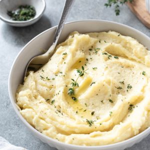Parsnip puree in a white bowl with serving spoon digging in