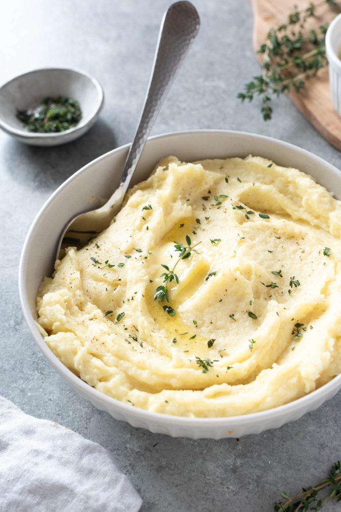 Parsnip puree in a white bowl with serving spoon digging in