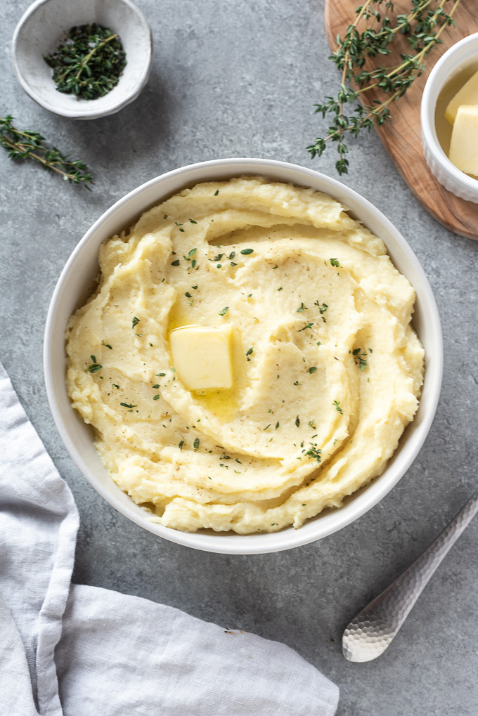 Parsnip mash in a bowl with a pat of butter and thyme leaves