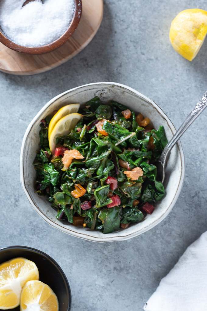 Sautéed swiss chard in a white bowl with a fork digging in