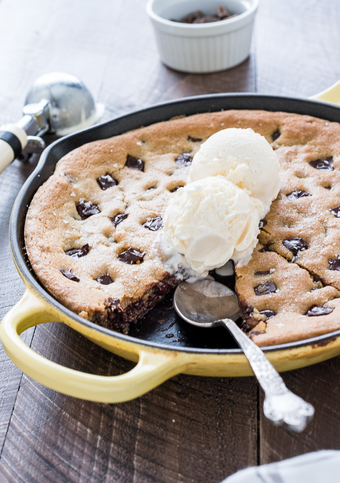 Skillet chocolate chip cookie sliced in the pan with ice cream