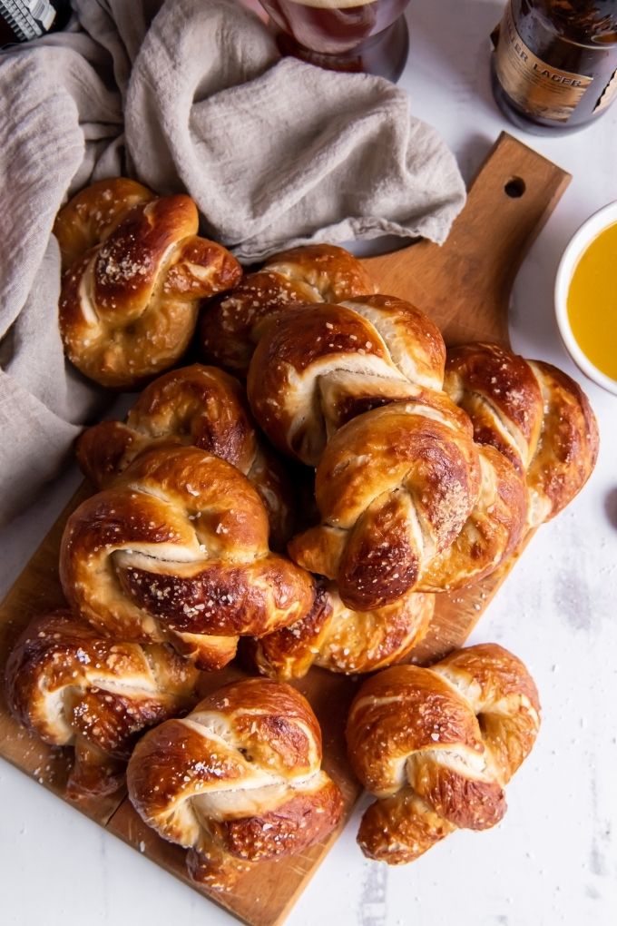 Soft pretzels piles on a cutting board with mustard sauce