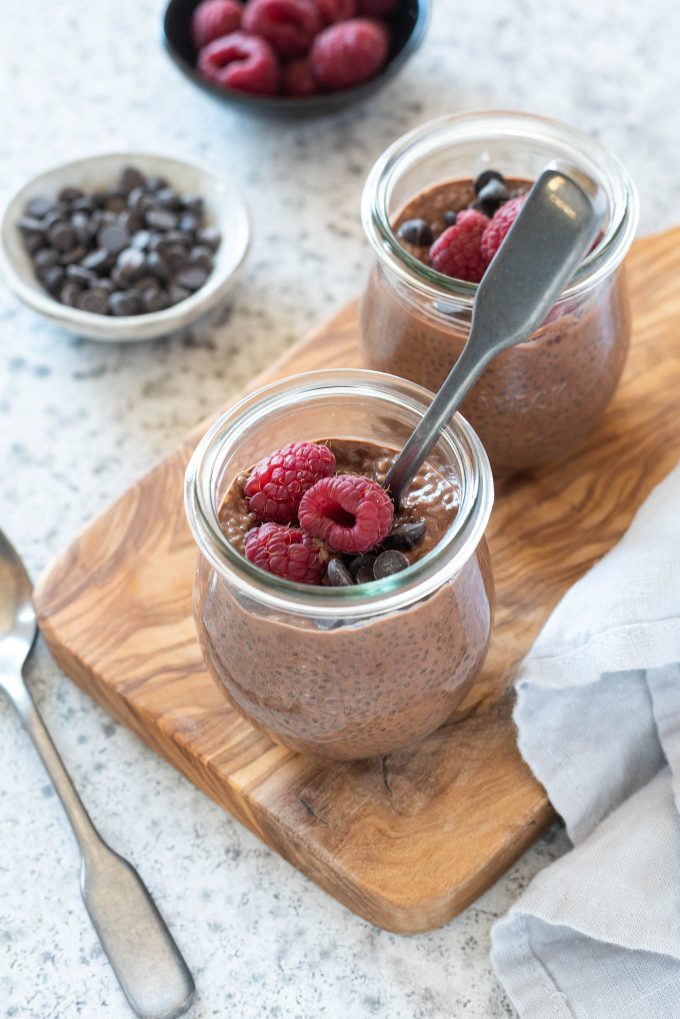 Chocolate Chia Pudding in jars with raspberries on top