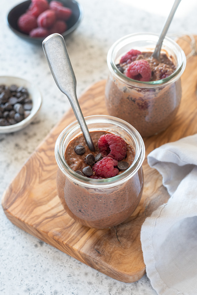 Jars of chocolate chia seed pudding with spoons digging in