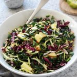 Kale slaw in a white bowl with honey lime dressing