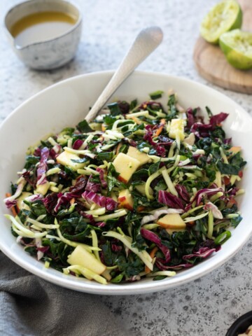 Kale slaw in a white bowl with honey lime dressing