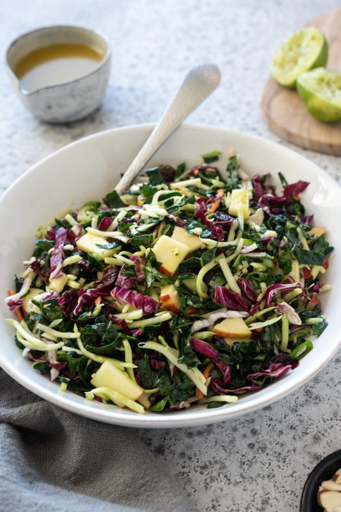 Kale slaw in a white bowl with honey lime dressing