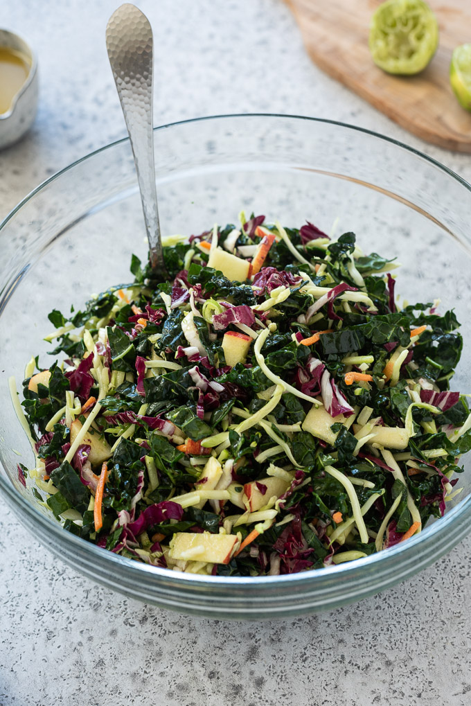Kale slaw tossed with honey lime dressing in a glass bowl